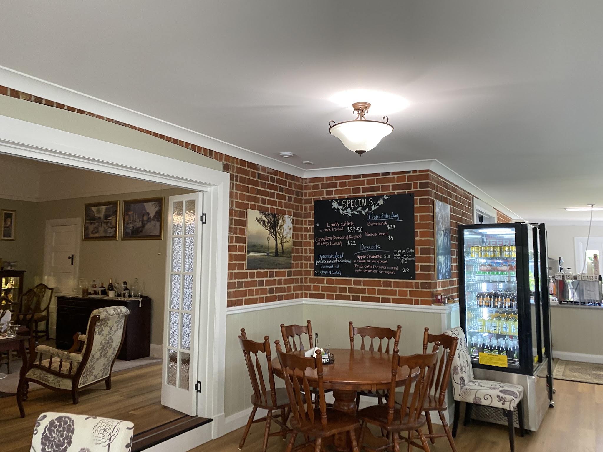 A dining nook with a round table, brick wall and the handwritten specials board