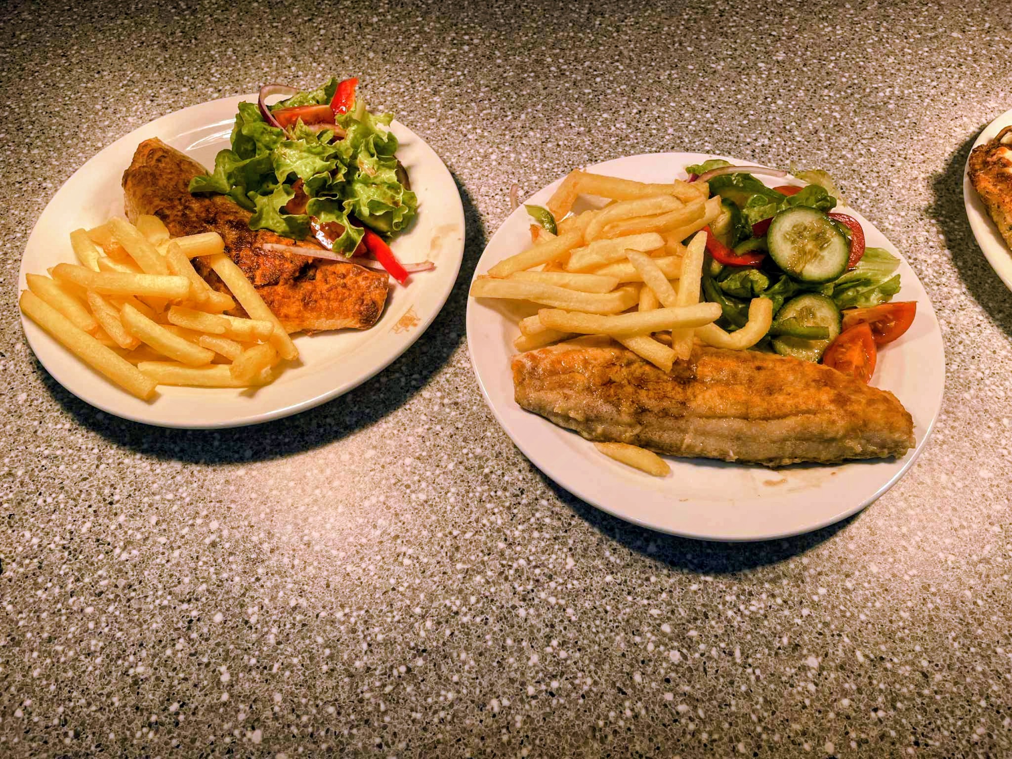 Two plates of crumbed fish with chips and salad