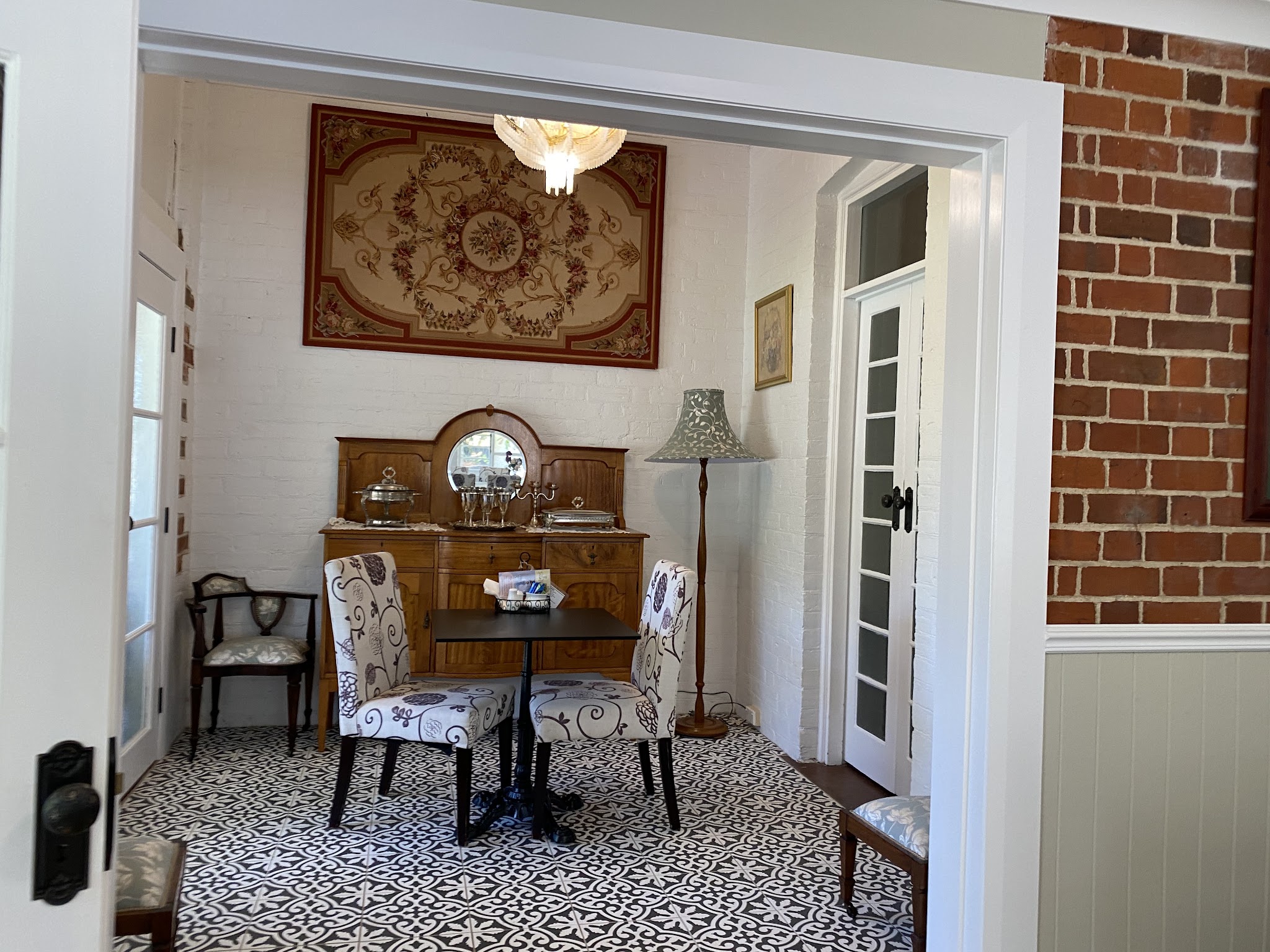 Antique sideboard, tapestry and patterned tile floor in the entry nook